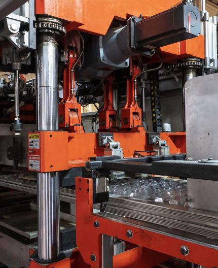 Vacuum thermoforming machine is used for producing plastic packaging in the factory. Close-up of the machine making a mold. Selective focus front
